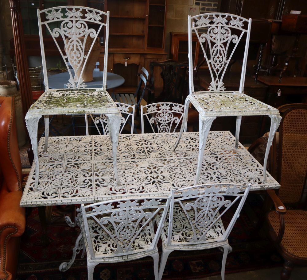 A white painted cast aluminium garden table, W.142cm, D.74cm, H.70cm and six chairs